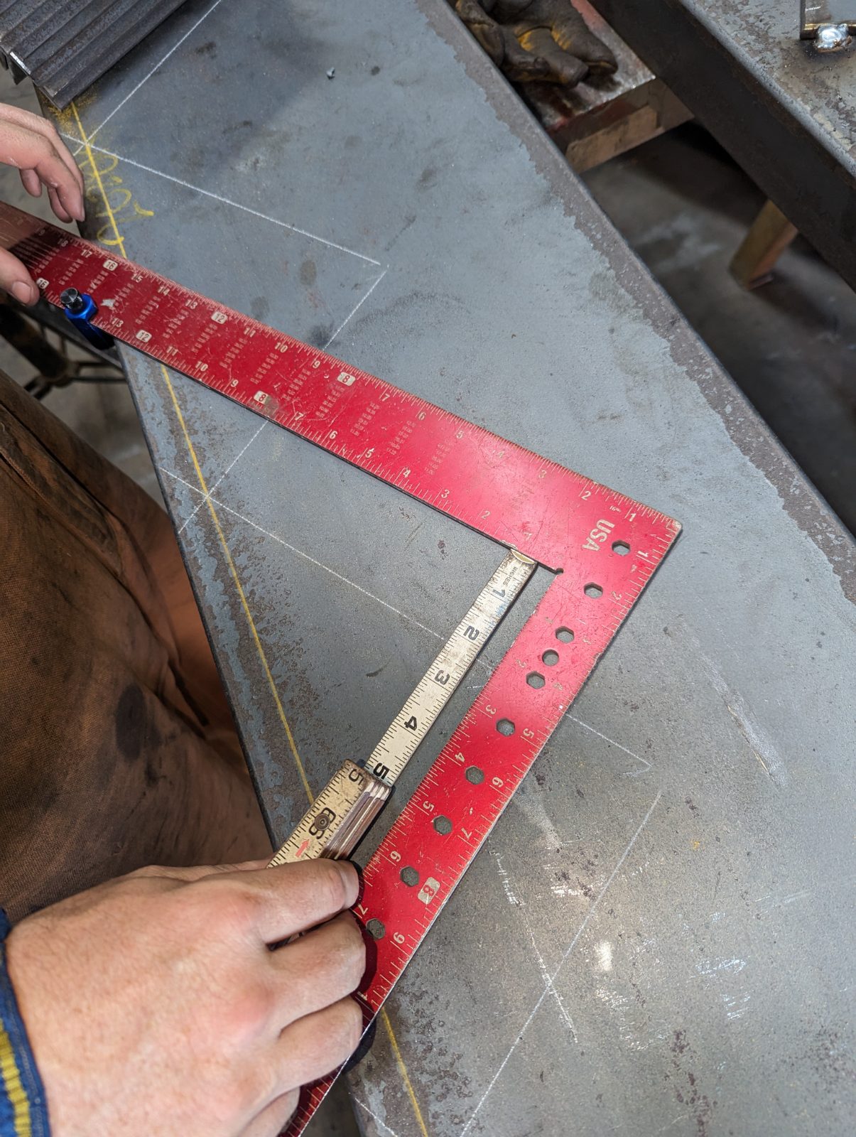 Framing square and folding rule laying out a cut on steel plate