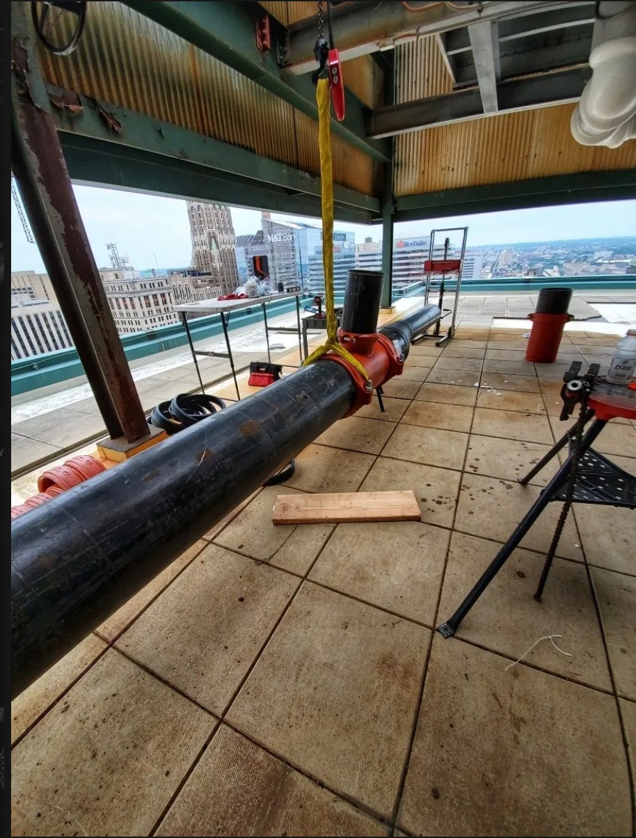 BA crew rooftop pipe job over the Baltimore skyline